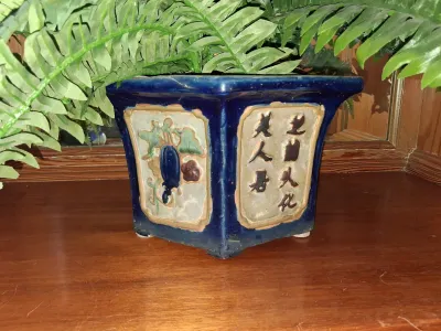 Sale Photo Thumbnail #93: Cobalt blue ceramic square planter with raised Chinese calligraphic characters and floral panels, housing a faux fern.