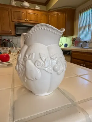 Sale Photo Thumbnail #463: Large white ceramic pitcher featuring embossed fruit motifs and beaded rim detailing.