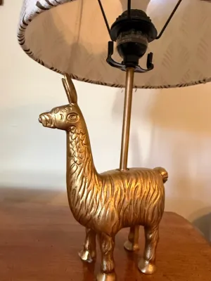 Sale Photo Thumbnail #364: Gold-painted llama novelty table lamp featuring a textured figural base and a patterned shade.