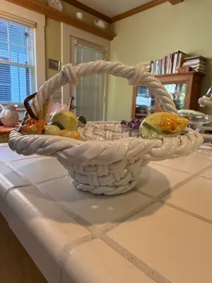 Sale Photo Thumbnail #493: Vintage Italian glazed ceramic woven fruit basket with integrated ceramic fruit details along the rim, resting on a tiled countertop.