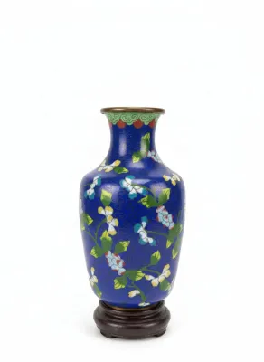 Sale Photo Thumbnail #5: Vintage Chinese cobalt blue cloisonné brass vase with a colorful floral and leafy vine design, resting on a carved dark wooden base.