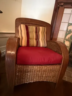 Sale Photo Thumbnail #195: Tropical-style woven wicker armchair featuring wide bentwood armrests, a solid red seat cushion, and a striped back cushion.