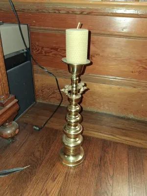 Sale Photo Thumbnail #114: Ornate brass candlestick holder featuring winged cherub details and a tiered stem, holding a honeycomb pillar candle.