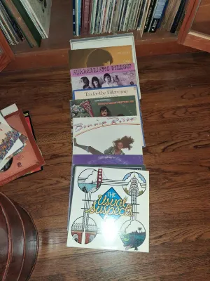 Sale Photo Thumbnail #118: Selection of vintage vinyl LP records laid out on a hardwood floor, including titles by Jefferson Airplane, Cat Stevens, and Bonnie Raitt.