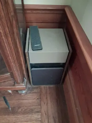 Sale Photo Thumbnail #91: Vintage Bose Acoustimass speaker cabinet with wood side panels and a remote resting on top.