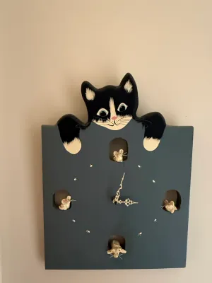 Sale Photo Thumbnail #421: Whimsical folk-art style wooden wall clock featuring a painted tuxedo cat peering over the top and tiny mice popping out of the clock face cutouts.