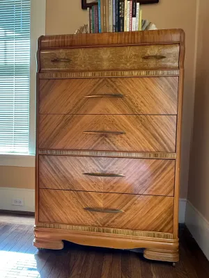 Sale Photo Thumbnail #207: Vintage Art Deco waterfall tallboy dresser featuring book-matched wood veneers and stylized metal pulls.