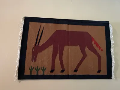 Sale Photo Thumbnail #196: Hand-woven flat-weave textile tapestry featuring an antelope or gemsbok figure, mounted on a plain wall.