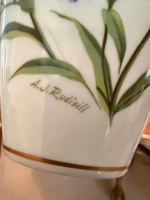 Sale Photo Thumbnail #133: Close-up of artist signature 'A.J. Rudisill' on a floral painted porcelain piece.