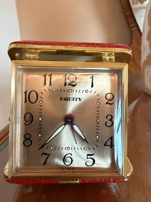Sale Photo Thumbnail #261: Vintage Equity travel alarm clock with a square gold-tone face and red faux-leather folding case, made in Taiwan.