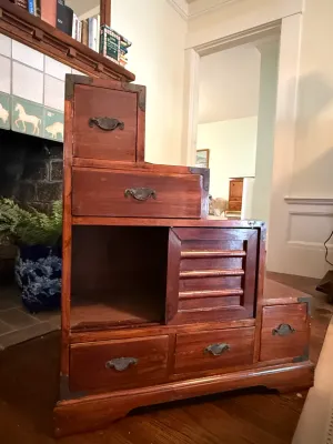 Sale Photo Thumbnail #180: Japanese step tansu chest (kaidan tansu) in a rich reddish-brown finish, featuring metal hardware, multiple drawers, and a sliding door compartment.