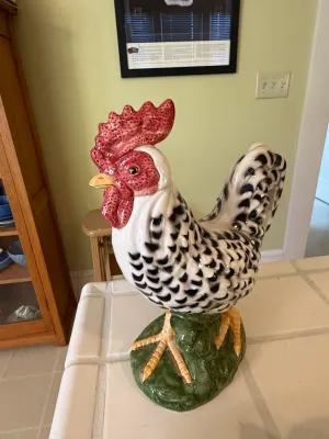 Sale Photo Thumbnail #441: Large glazed ceramic rooster figurine featuring black and white barred feathers, a red comb, and a green base, standing on a tiled countertop.