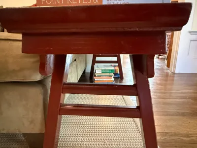 Sale Photo Thumbnail #212: Red-painted Asian-style wooden bench with crossbar supports, shown with books stacked beneath it.
