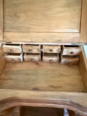 Sale Photo Thumbnail #319: Interior view of a vintage wooden slant-top writing desk featuring eight small organizer drawers with matching wooden knobs.