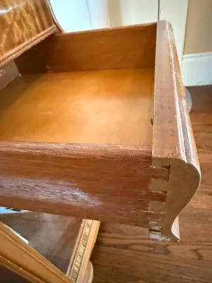 Sale Photo Thumbnail #250: Open wooden drawer of an antique desk or cabinet, featuring dovetail construction and finish wear along the edges.