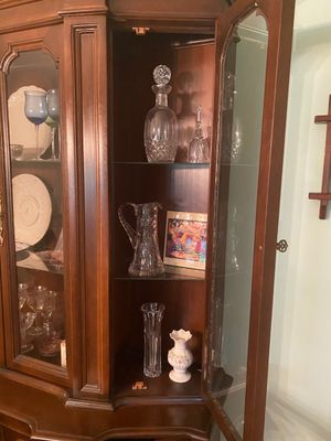 Vintage dark wood china cabinet filled with assorted crystal glassware, decanters, and decorative ceramics.