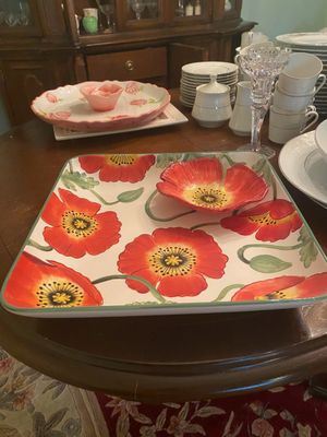 Hand-painted ceramic chip and dip tray featuring a red poppy floral pattern, displayed alongside other tableware on a dark wood dining...
