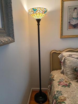 Tiffany-style stained glass torchiere floor lamp featuring colorful floral and geometric motifs on a dark metal base.