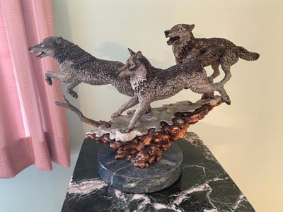 Detailed wildlife sculpture titled "Yellowstone Bound" depicting a pack of running wolves mounted on a marble base.