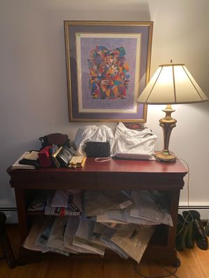 Traditional wooden console table displayed with various women's handbags, dust bags, and men's dress shirts on the lower...