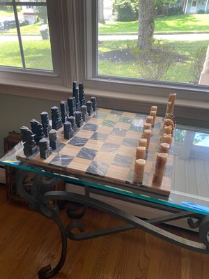 Hand-carved marble or stone chess set with architectural stylized pieces, displayed on a matching checkerboard top.