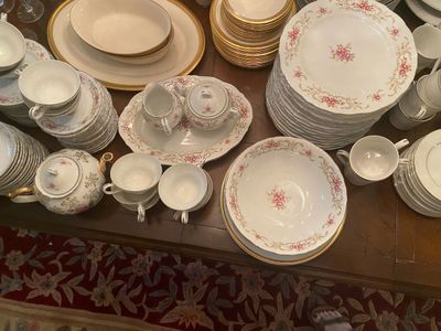 Extensive vintage fine china dinnerware service featuring pink floral transfers, gilded rims, teacups, serving platters, and a teapot.