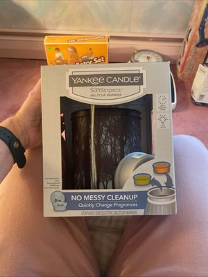Yankee Candle Scenterpiece electric meltcup warmer in original retail packaging, featuring a dark brown laser-cut forest silhouette design.
