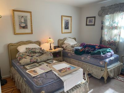 Bedroom set featuring twin beds with French Provincial style headboards and footboards, framed art prints, a stained glass lamp, and...