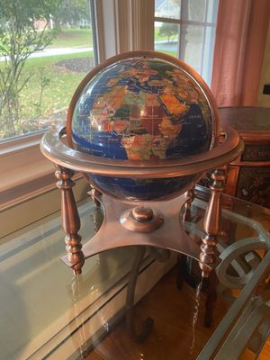 Gemstone world globe with lapis lazuli oceans, resting on a copper-toned metal tripod stand with full meridian and horizon rings.