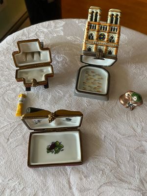 Collection of hinged Limoges porcelain trinket boxes, including cathedral, book, and artist's easel designs.