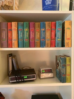 A collection of vintage Companion Library hardback children's books arranged on a white shelf alongside vintage digital alarm clocks.