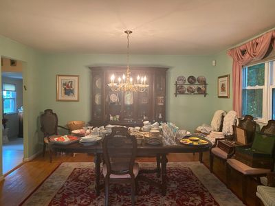 Traditional dining room set including a large dark wood dining table, matching cane-back chairs, and a large display china cabinet loaded...