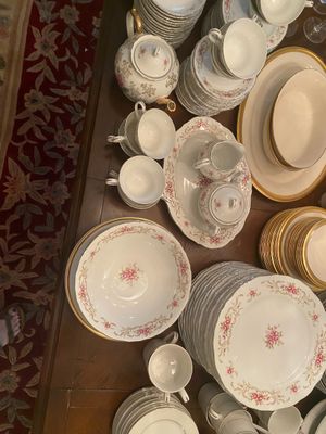 Extensive vintage fine china dinnerware service featuring pink floral transfers, gilded rims, teacups, serving platters, and a teapot.