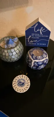 Sale Photo Thumbnail #27: Collection of home decor items featuring a wooden house-shaped sign, a mirrored mosaic candle holder, a blue and white decorative candle, and a Boston Tea Party ceramic ornament.