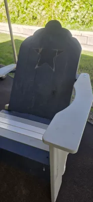 Sale Photo Thumbnail #60: Two-tone rustic Adirondack-style chair featuring a black backrest with a carved star motif and light gray seat and armrests.