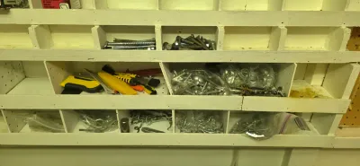 Sale Photo Thumbnail #24: A painted white wooden bin organizer filled with assorted hardware, screws, bolts, and small hand tools.