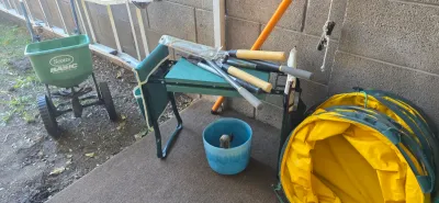 Sale Photo Thumbnail #53: Collection of outdoor and gardening equipment, including a Scotts broadcast spreader, folding garden kneeler seat, long-handled pruning tools, and pop-up lawn bags.