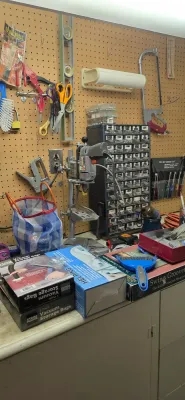 Sale Photo Thumbnail #26: Workshop workbench area featuring a small benchtop drill press stand, a multi-drawer hardware organizer, and various hand tools hung on a pegboard.