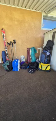 Sale Photo Thumbnail #58: Assortment of vintage outdoor and sports gear, including Völkl snow skis, ski poles, golf bags with push cart, and various duffle bags.