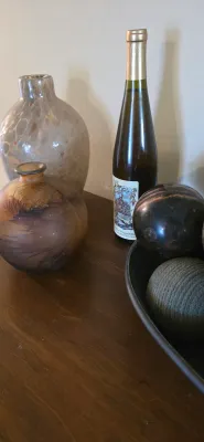 Sale Photo Thumbnail #4: Collection of decorative tabletop accents including art glass vases, a wine bottle, and decorative spheres displayed on a wooden surface.