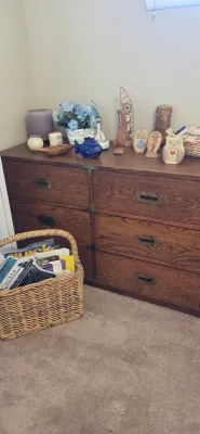 Sale Photo Thumbnail #41: Rustic oak campaign-style six-drawer dresser with recessed brass hardware, topped with home decor items and paired with a wicker basket.