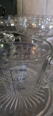 Sale Photo Thumbnail #36: Anchor Hocking 1-cup clear glass measuring cup with blue measurement markings, shown alongside other glassware.