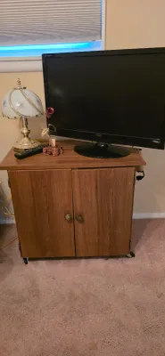 Sale Photo Thumbnail #43: AOC flat-screen computer monitor and small touch-lamp displayed on a mobile wood-tone media cabinet with two doors.