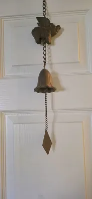 Sale Photo Thumbnail #33: Vintage cast metal hanging bell chime featuring a winged pig motif, a bell, and a diamond-shaped wind catcher.
