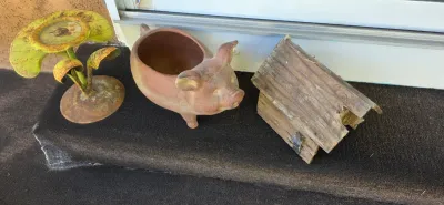 Sale Photo Thumbnail #63: Collection of rustic garden decor, including a metal lotus candle holder, a terracotta pig planter, and a weathered wooden birdhouse.