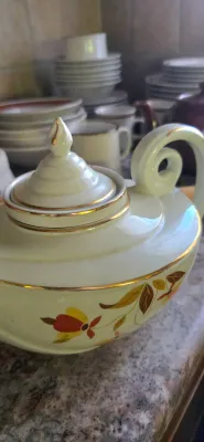 Sale Photo Thumbnail #37: Vintage ceramic teapot featuring gold trim, a swirl handle, and a autumn-toned floral design.