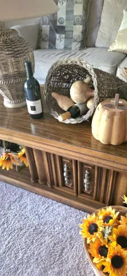 Sale Photo Thumbnail #7: Vintage wooden coffee table with carved detail doors, styled with a textured ceramic lamp, woven cornucopia, wine bottles, and autumn decor.