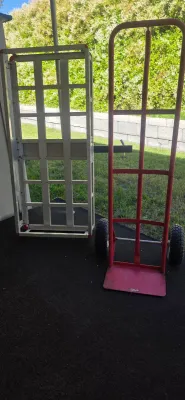 Sale Photo Thumbnail #59: Red heavy-duty hand truck with pneumatic tires alongside a collapsible aluminum cart frame.