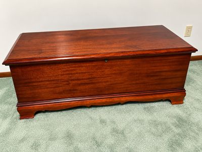 Sale Photo Thumbnail #30: Traditional cherry-finish cedar chest featuring a keyhole lock, molded top edge, and bracket feet.