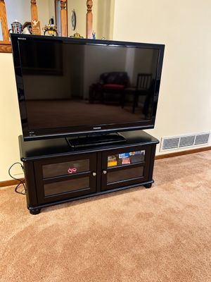 Sale Photo Thumbnail #14: Toshiba Regza flat-screen television resting on a black wooden media console with glass-front cabinet doors.